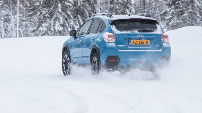 Ein hellblauer Subaru XV fährt 2016 durch eine Winterlandschaft.