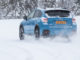 Ein hellblauer Subaru XV fährt 2016 durch eine Winterlandschaft.