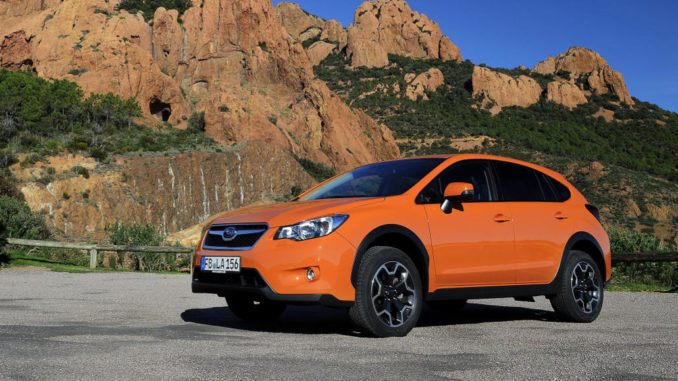 Ein orangener Subaru XV steht 2012 vor ockerfarbenen Felsen.