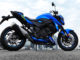 Eine blaue Suzuki GSX-S750 steht auf einer Betonfläche vor einer Skyline.