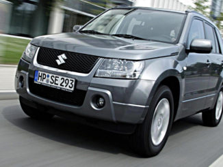 Ein silberner Suzuki Grand Vitara fährt 2005 an einem Bürogebäude vorbei.