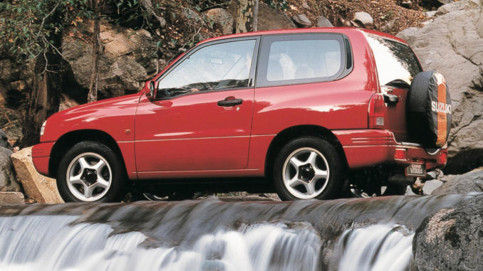 Ein roter Suzuki Grand Vitara Limousine 2.0 Liter fährt 1998 über einen Wasserfall.