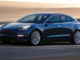 Ein blauer Tesla Model 3 fährt 2018 durch eine Wüstenlandschaft.