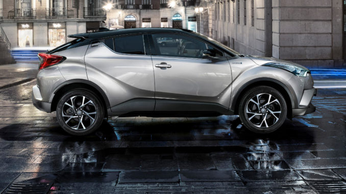 Ein silberner Toyota C-HR steht auf einem regennassen Stadtplatz.