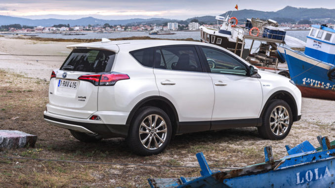 Ein weißer Toyota RAV4 Hybrid steht 2016 an einem kleinen Mittelmeerhafen zwischen Schiffen.