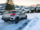 Ein silberner Toyota C-HR bremst auf schneeglatter Landstraße in den Alpen.