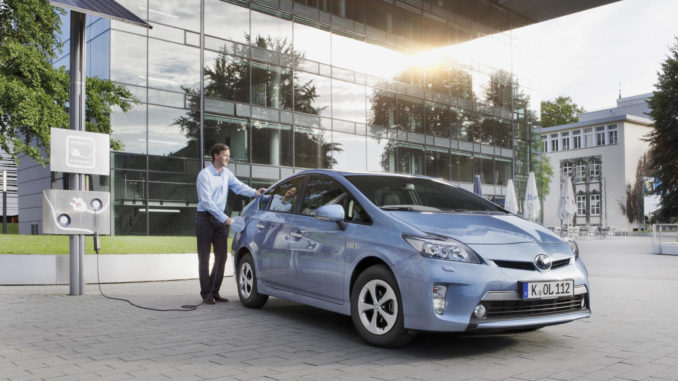 Ein blauer Toyota Prius PHV steht 2014 an einer Ladesäule.