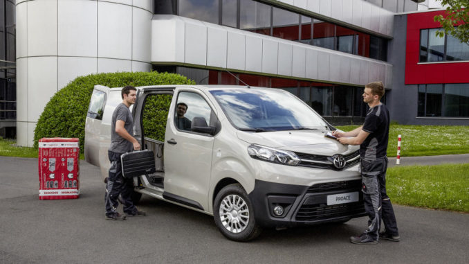 Ein beiger Toyota Proace wird von zwei Handwerkern beladen.