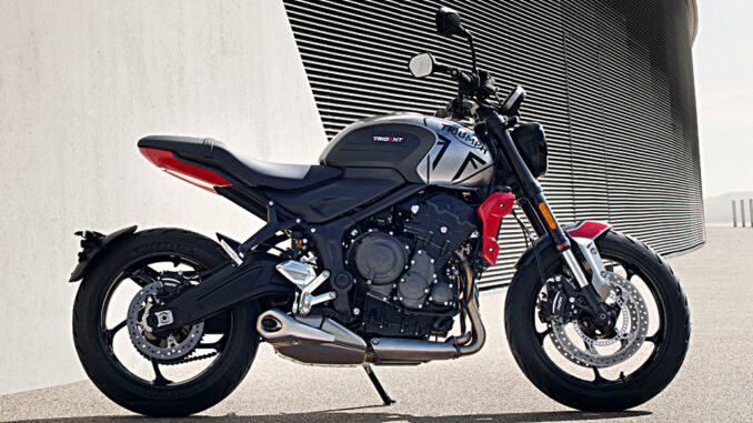 Eine silber-rote Triumph Trident steht 2020 vor einem Betongebäude.