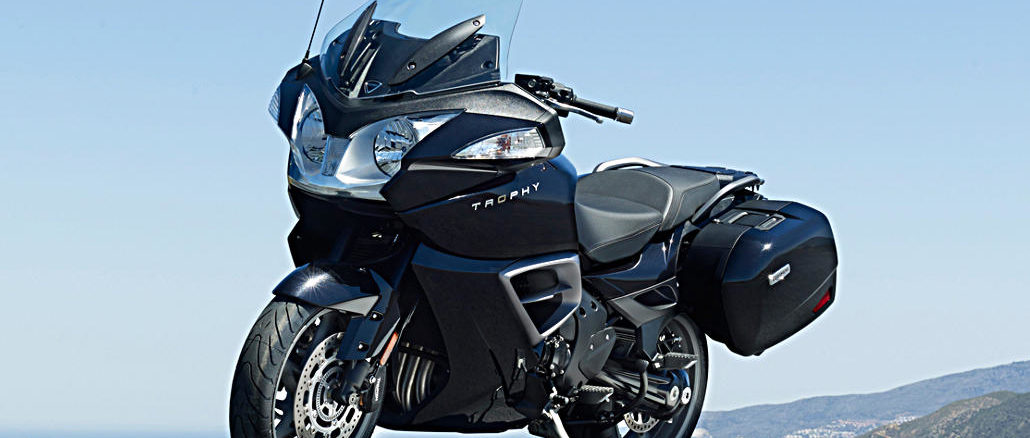 Eine schwarze Triumph Trophy SE steht auf einer Teerfläche im Sonnenschein.