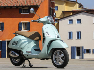 Eine türkise Vespa GTS 300 steht 2019 auf einem italienischen Dorfplatz.