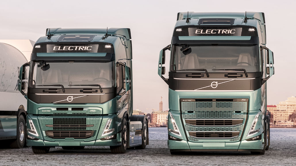Die türkisfarbenenen Volvo Trucks FM und FH Electric stehen 2021 an einem Hafen.