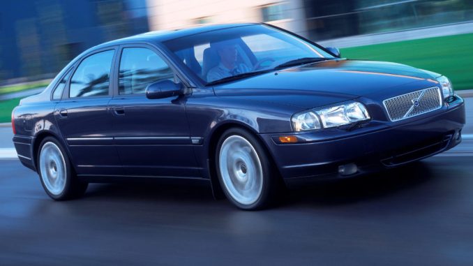 Ein blauer Volvo S80 fährt 2004 an einem Bürogebäude vorbei.