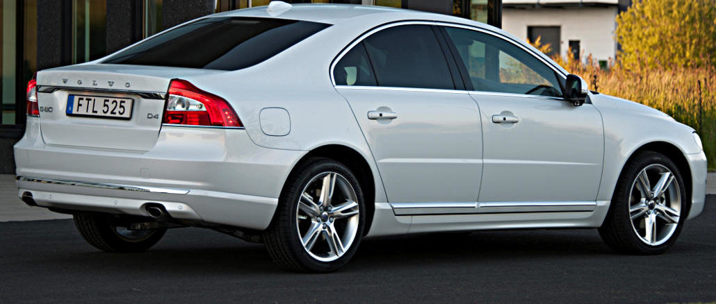 Ein weißer Volvo S80 steht 2018 vor dem Eingang zu einem Bürogebäude in Schweden.