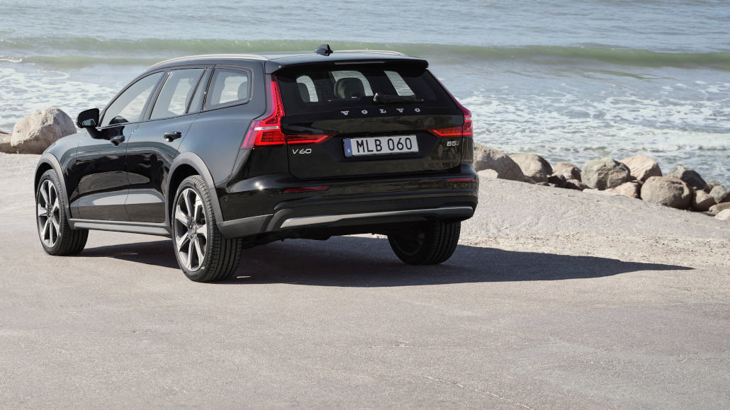 Ein Volvo V60 Cross Country B5 AWD, Außenfarbe Onyx Black Metallic, Heck, Seitenansicht, steht 2022 am Wasser.