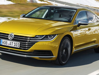 Ein goldener VW Arteon fährt durch eine verschneite Landschaft.