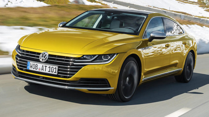 Ein goldener VW Arteon fährt durch eine verschneite Landschaft.