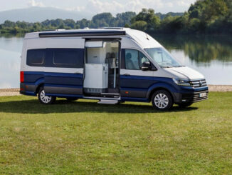 Ein blau-weißer VW Crafter Grand California 680 steht 2018 an einem See.