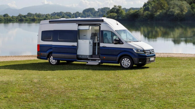 Ein blau-weißer VW Crafter Grand California 680 steht 2018 an einem See.