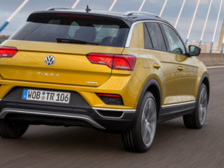 Ein goldener VW T-Roc fährt über eine Brücke.