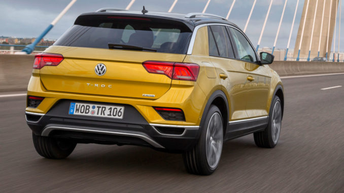 Ein goldener VW T-Roc fährt über eine Brücke.