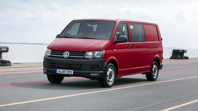 T-Baureihe / Transporter / Kastenwagen T6 von VW in rot fährt einen Hafenkai entlang.