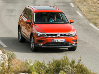 Ein roter VW Tiguan Allspace fährt auf einer mediterranen Landstraße.