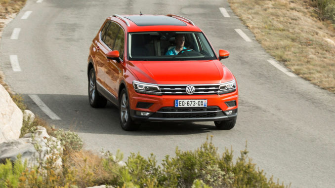 Ein roter VW Tiguan Allspace fährt auf einer mediterranen Landstraße.