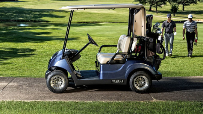 Ein blaues Golf Cart von Yamaha, modell Drive2, steht auf einem Weg am Rande eines Platzes.