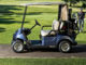 Ein blaues Golf Cart von Yamaha, modell Drive2, steht auf einem Weg am Rande eines Platzes.